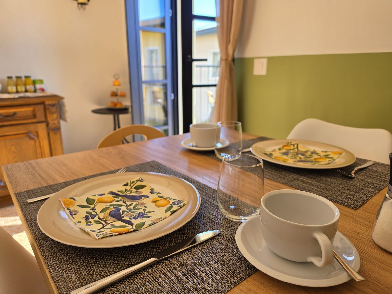 Un coperto apparecchiato con il piatto decorato e la tazza, davanti alla finestra