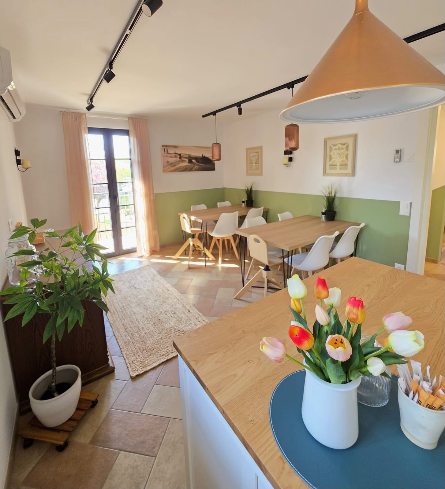 La sala colazioni del B&B Airone, luminosa, con i tavoli apparecchiati e i tulipani sul bancone