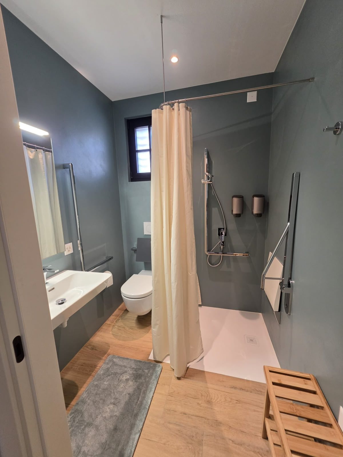 Il bagno accessibile di Magnolia, con doccia a filo pavimento, maniglioni e spazio per muoversi in sedia a rotelle