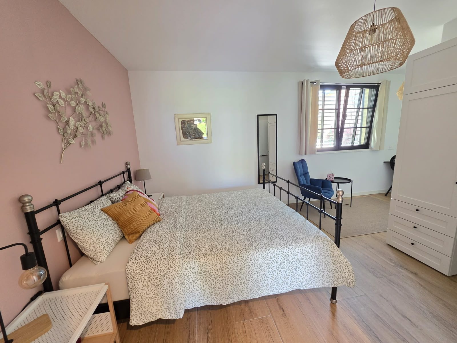 La camera Magnolia al piano terra: letto matrimoniale, parete rosa e finestra con le persiane