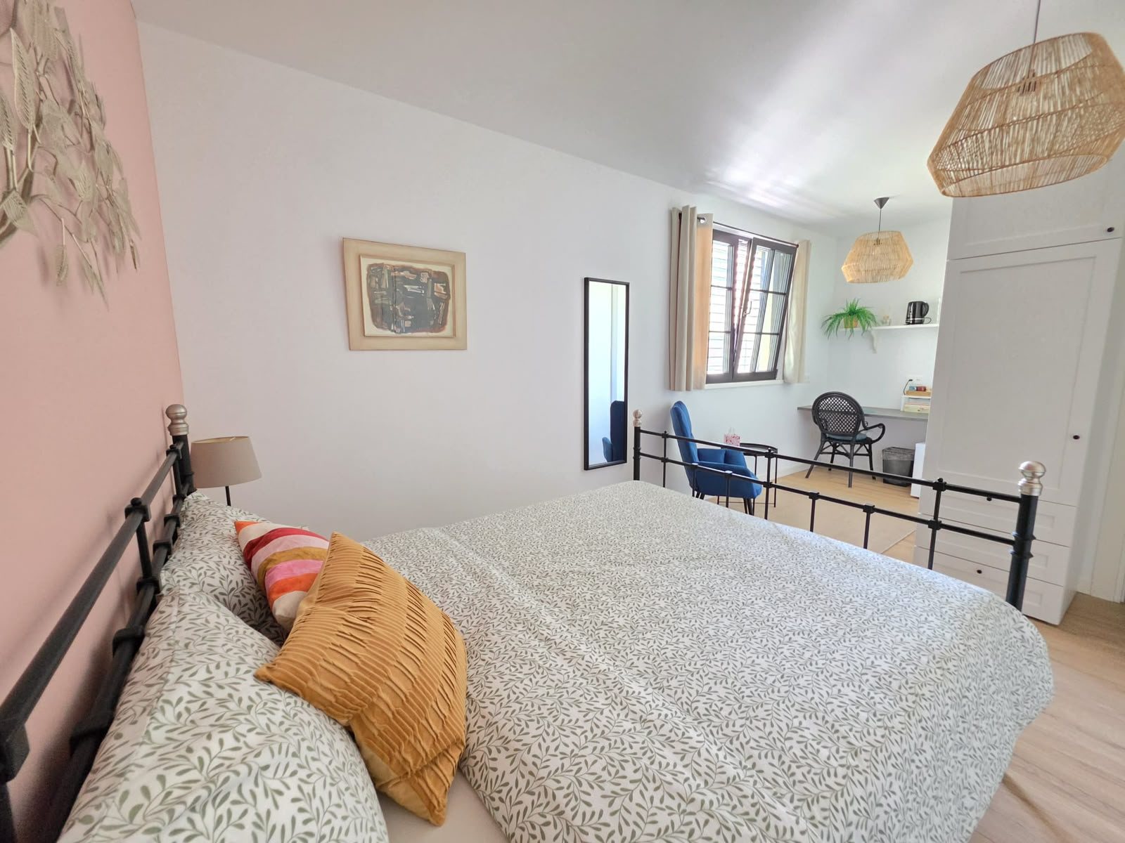 La camera Magnolia al piano terra: il letto matrimoniale in ferro, la poltrona blu e, vicino alla finestra, la scrivania con l’angolo caffè