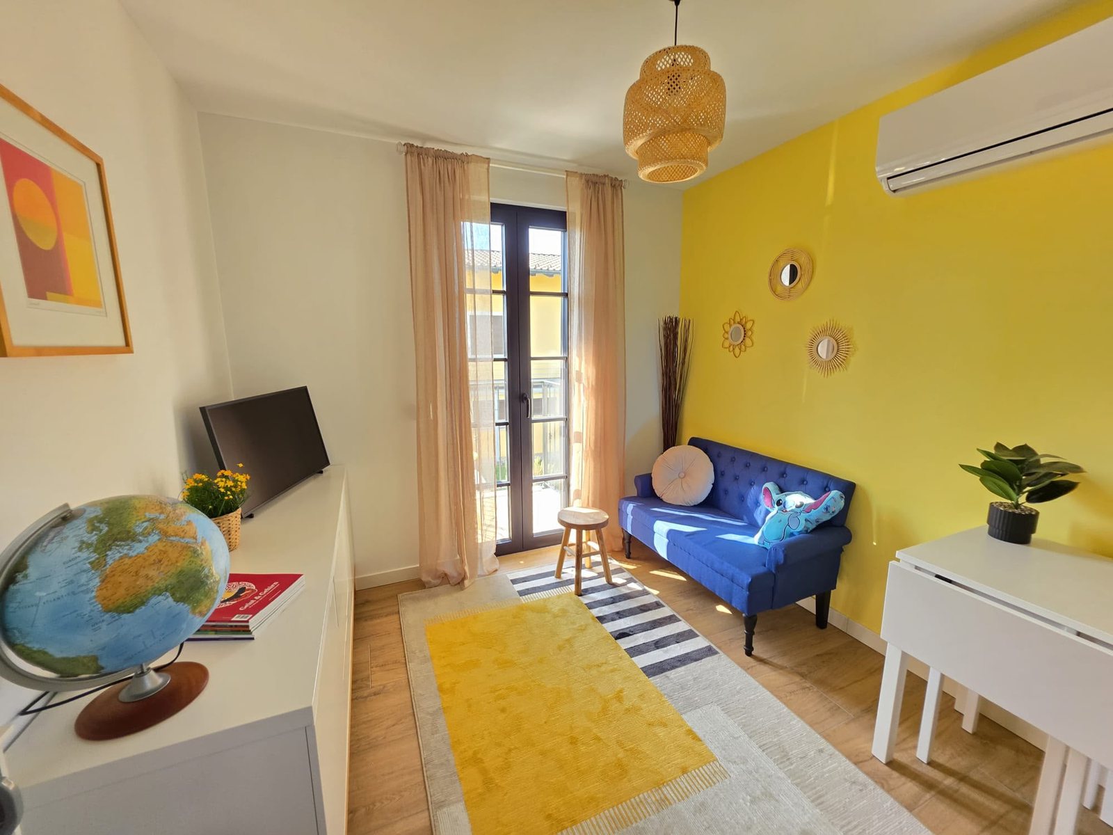 L'angolo relax del locale svago, con la televisione, il divano blu e il tappeto giallo